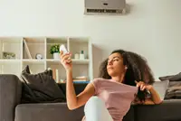 Black woman trying to get her wall-mounted AC to turn back on